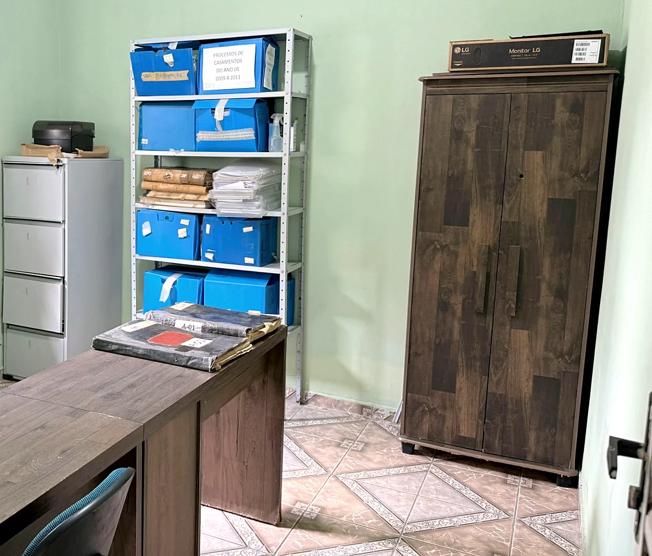 Sala do acervo, com livros de registro sobre a mesa e caixas de processos nas estantes
